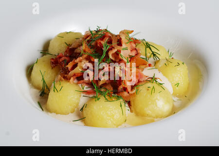 Close-up di gnocchi, la pancetta affumicata e salsa alla panna su un tavolo di legno. Foto Stock