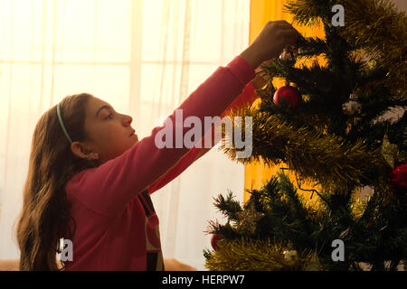 Ragazza decorare un albero di Natale Foto Stock