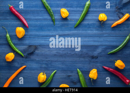 Cayenne peperoncino habanero giallo peperoni blu sul tavolo di legno Foto Stock