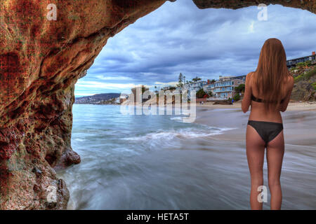 Tramonto hits case lungo Pearl Street Beach come una donna coetanei attraverso una roccia toppa in Laguna Beach, California, Stati Uniti d'America Foto Stock