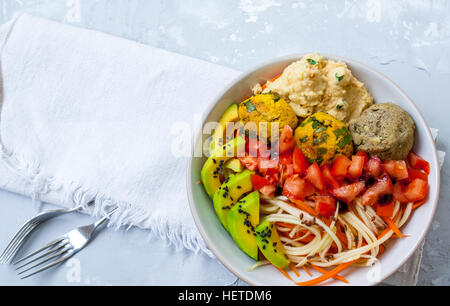 Zucchine, carote spaghetti con sfere vegana, avocado e hummus. Vista dall'alto sul cemento grigio Sfondo. Cibo Vegan concetto. Foto Stock