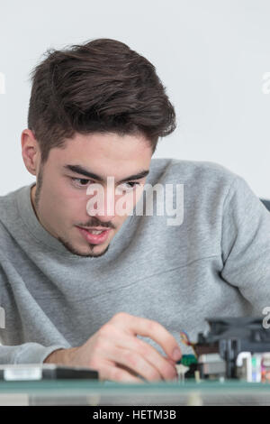 Giovane bello computer riparatore concentrato sul suo lavoro Foto Stock