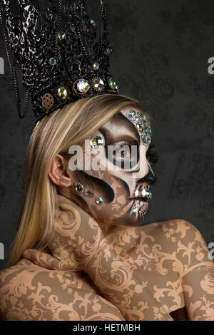 Il giorno dei morti scintillante trucco creativo nel cranio di caramella stile con gioielli in argento, corona gotica e damasco body paint Foto Stock