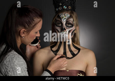 Make up Artist mette tocchi di rifinitura per il Giorno dei Morti scintillante trucco creativo guarda sul modello in studio fotografico Foto Stock