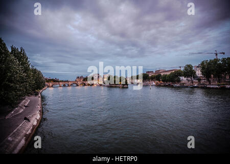 Alba di un mattino nuvoloso a Parigi in Francia con Ile de la Cite e Pont Neuf. Il fiume Senna riflette il cielo violetto e luci della citta'. Foto Stock