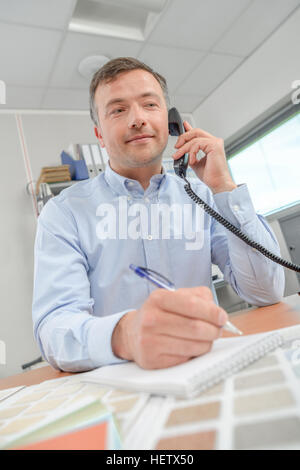 Uomo al telefono i grafici a colori davanti a lui Foto Stock