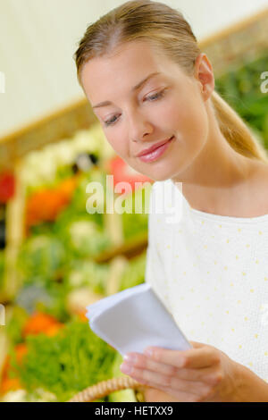 Signora consultando la lista della spesa Foto Stock