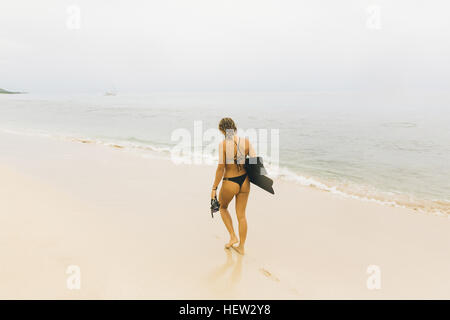 Nuotatore portando pinne, passeggiate sulla spiaggia Foto Stock