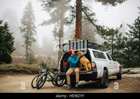 Uomo e cane seduti sul portellone del fuoristrada, Sequoia National Park, California, Stati Uniti d'America Foto Stock