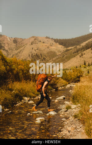L'uomo, indossando uno zaino, attraversando creek, minerale re, Sequoia National Park, California, Stati Uniti d'America Foto Stock