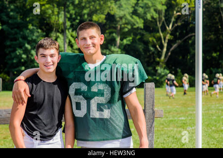 Ritratto maschile teenage giocatore di football americano con il braccio intorno all amico sul campo da gioco Foto Stock