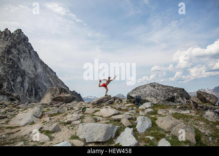 Giovane donna in piedi sulla roccia, yoga in posa, gli incanti, Alpine Lakes Wilderness, Washington, Stati Uniti d'America Foto Stock