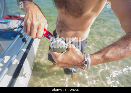 L'uomo tirando il gancio dal pesce la bocca dopo essere stati catturati, metà sezione, Fort Walton Beach, Florida, Stati Uniti d'America Foto Stock