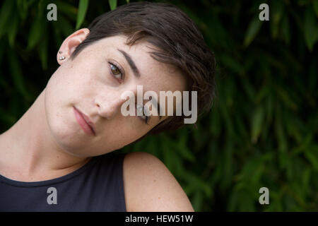 Ritratto di giovane donna con capelli ritagliata, all'aperto, pensieroso expression Foto Stock