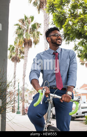 Giovane uomo Bicicletta Equitazione, sorridente Foto Stock