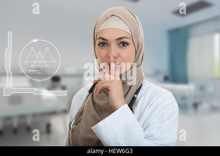 Closeup ritratto di amichevole e fiducioso con musulmani hijab medico mostrando shh sospiro, silenzio. Foto Stock