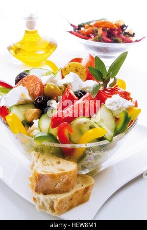 Insalata greca in una ciotola di vetro con il formaggio feta, cetriolo, pomodoro, peperoncino, e verde e olive nere e servita con Foto Stock