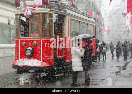 Tram Nostalgico di Istanbul e bagel venditore in istiklal street e la gente a piedi su Via Istiklal sotto la neve a Istanbul Foto Stock