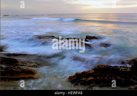Questa fotografia del mare di Tasman al tramonto mostra un tranquillo paesaggio marino sulla spiaggia, con onde dolci e un cielo ricco e caldo. La scena cattura la serenità della costa, con l'oceano che incontra l'orizzonte in una splendida mostra di bellezza naturale. Foto Stock