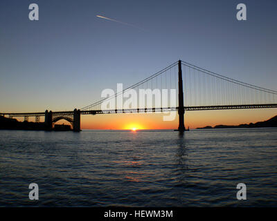 Una splendida foto del Golden Gate Bridge di San Francisco durante il tramonto, che cattura l'iconico ponte contro il cielo vibrante. L'immagine evidenzia la bellezza architettonica del ponte mentre contrasta con il cielo colorato. Foto Stock