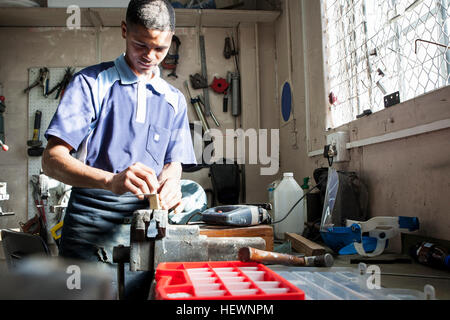 Giovane uomo che lavora a morsa in officina di riparazione Foto Stock