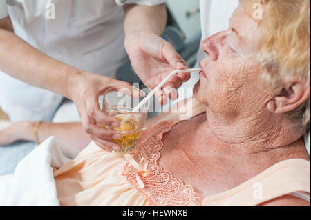 Infermiere aiutare il paziente nel letto di ospedale prendere un drink Foto Stock