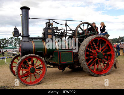 Questa fotografia cattura un motore di trazione Burrell in azione durante un rally agricolo d'epoca. Il motore alimentato a vapore, noto per il suo colore rosso brillante, mostra l'evoluzione dei veicoli stradali a vapore e il ruolo chiave che hanno svolto nelle esposizioni storiche di macchinari agricoli e nei raduni di trattori. Foto Stock