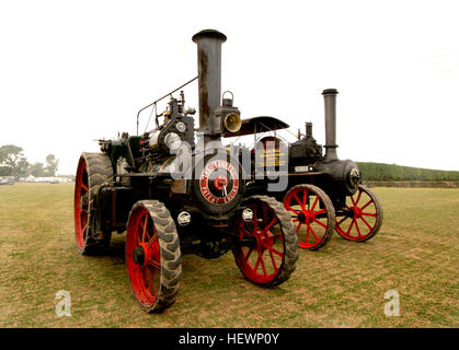 Questa fotografia cattura un motore di trazione Burrell durante un rally a vapore, mostrando gli impressionanti macchinari utilizzati nell'agricoltura di vecchio stile. Il motore a vapore, dipinto di rosso, riflette il progresso industriale dell'epoca e il suo ruolo vitale nello sviluppo agricolo durante il XIX secolo. Foto Stock