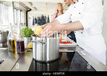 Lo Chef aggiungendo la pasta alla pentola Foto Stock