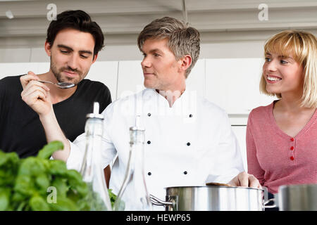 Lo chef e il giovane in cucina cibo degustazione Foto Stock