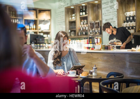 Giovane donna che guarda la tavoletta digitale in cafe Foto Stock