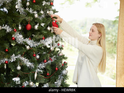 Ragazza adolescente appeso decorazioni su albero di natale Foto Stock