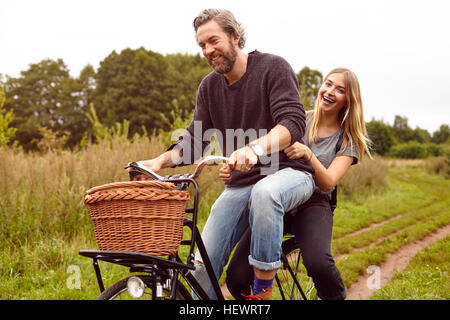 Ritratto di giovane di ridere mentre Bicicletta Equitazione su rurale dirt track Foto Stock