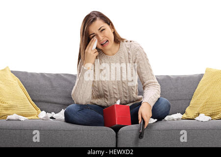 Triste giovane donna guardando la televisione su un divano e pianto isolati su sfondo bianco Foto Stock