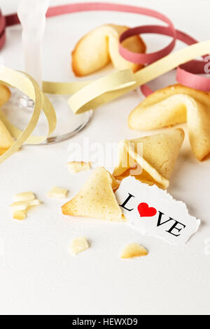 I cookie conformata come tortellini con la parola amore scritto su un foglio di carta e un bicchiere di champagne con streamers.immagine verticale. Foto Stock