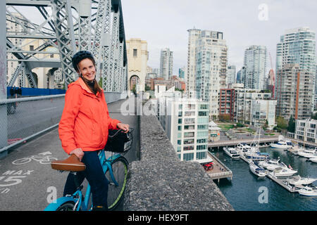 Ritratto di giovane donna pronto a guidare la bicicletta su ciclabile, Vancouver, British Columbia, Canada Foto Stock