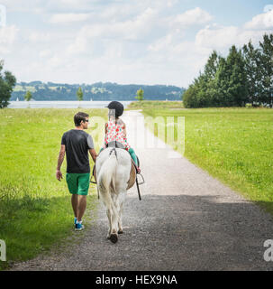 Vista posteriore del padre figlia di guida di equitazione, Fuessen, Baviera, Germania Foto Stock