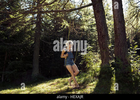 Metà donna adulta seduto sulla foresta swing, Sattelbergalm, Tirolo, Austria Foto Stock