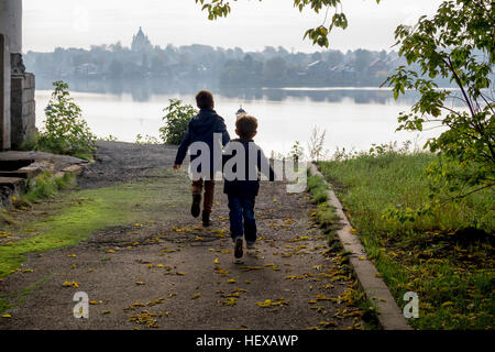 Vista posteriore di due giovani fratelli che corre verso il Riverside, Ural, Russia Foto Stock