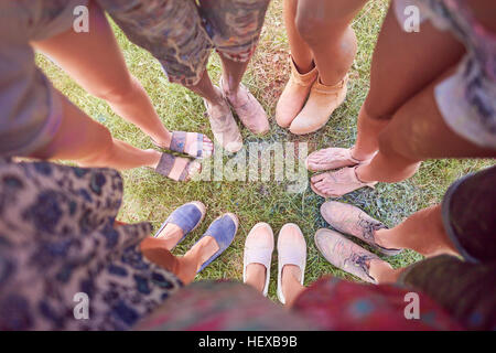 Gruppo di amici al festival, coperto di polvere colorata vernice, stando in piedi in cerchio, vista in elevazione dei piedi Foto Stock