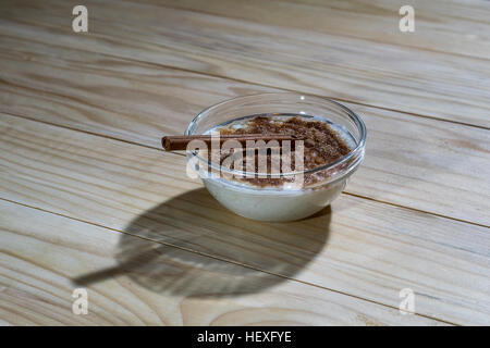 Cremoso budino di riso con cannella in polvere e la stecca di cannella su una tavola di legno Foto Stock