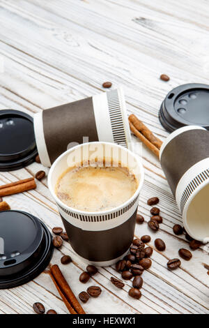 Bicchieri di carta di cappuccino, cannella e chicchi di caffè Foto Stock