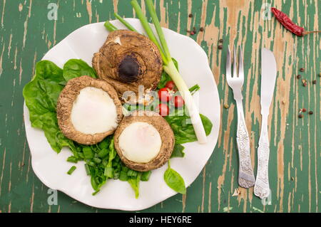 Uovo Funghi ripieni su una piastra su un vintage tavolo verde Foto Stock