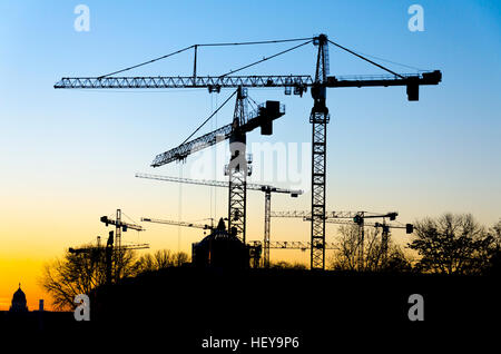 Silhouette di gru edili in serata durante lo skyline di Berlino, Germania Foto Stock