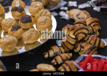 Parte cibo kosher a buffet - profiteroles, rugelach e caramelle sulla tovaglia nero Foto Stock