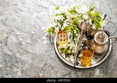 Bicchieri di tè e pot. Oriental vasellame in argento. Fiori di Primavera decorazione. Messa a fuoco selettiva Foto Stock