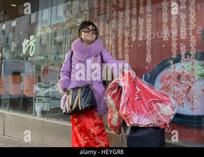 Un americano cinese donna che indossa un tradizionale abito da sposa & trasporto un altro a Chinatown, il centro cittadino di lavaggio, Queens New York Foto Stock