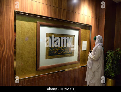 Un visitatore la lettura di un segno descrive il raro calligrafica display pannello presso il Santo Corano mostra. Medina, Arabia Saudita Foto Stock