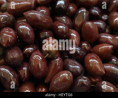 Kalamata Greco nero rosso lucido intero delle olive in olio vicino fino sfondo, sul mercato al dettaglio di stallo, display a basso angolo di visione Foto Stock