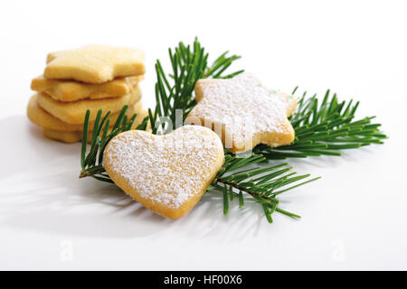 A forma di cuore e a forma di stella frollini biscotti di Natale su un ramoscello di abete, decorazione di Natale Foto Stock